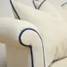Curved Sofa Reupholstered in a Cream Fabric with Dark Contrast Piping
